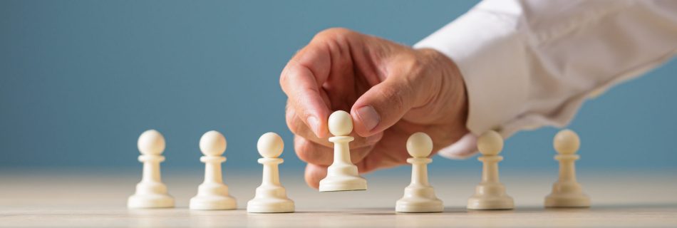 Wide view image of businessman placing pawn chess piece along with the others in a conceptual image.