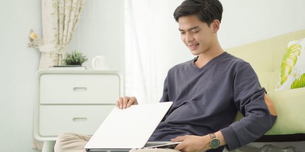 handsome asian man turning off his laptop after working at home